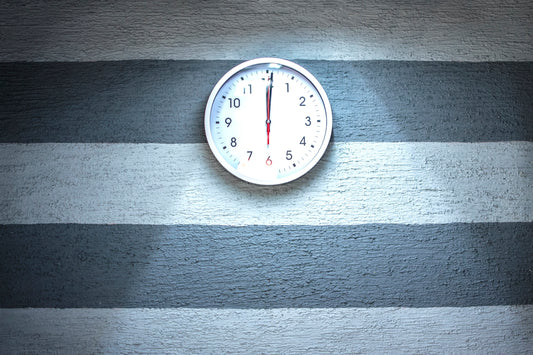 white analog wall clock reading at 12L00