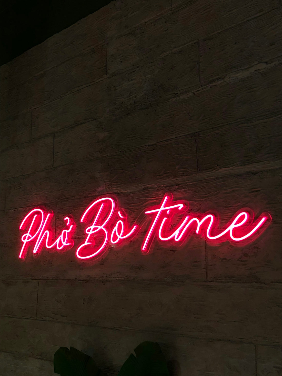 a neon sign that says pho bo time on a wall