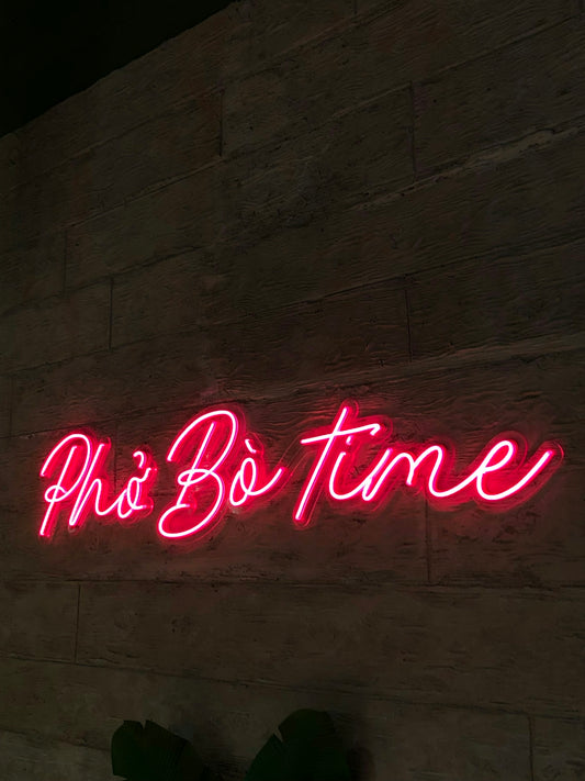 a neon sign that says pho bo time on a wall