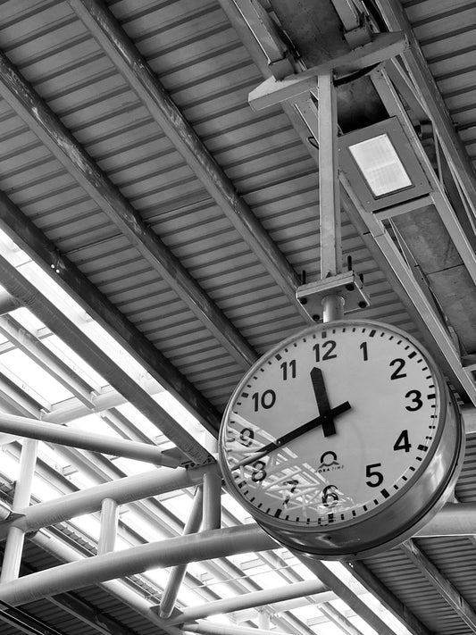 a clock hanging from the ceiling of a train station
