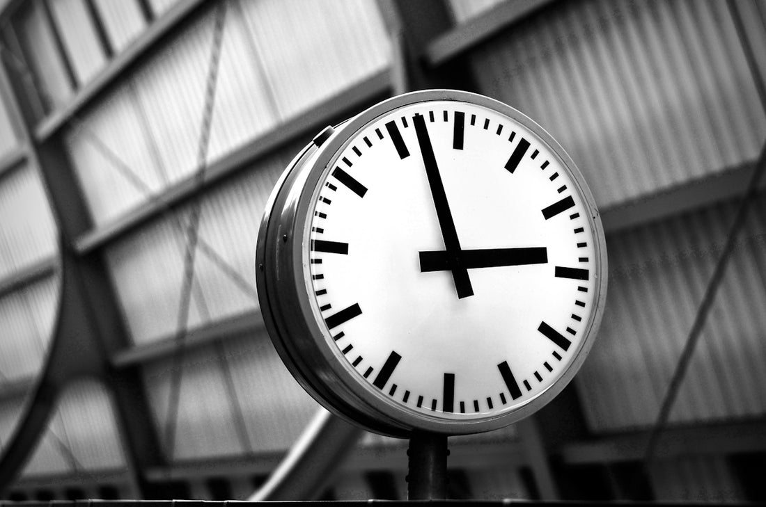 A black and white photo of a clock in a train station