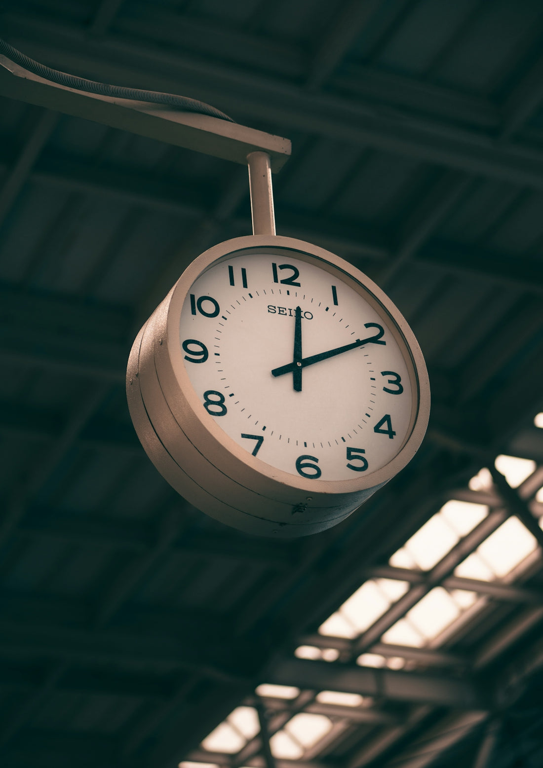 A clock hanging from the ceiling of a train station
