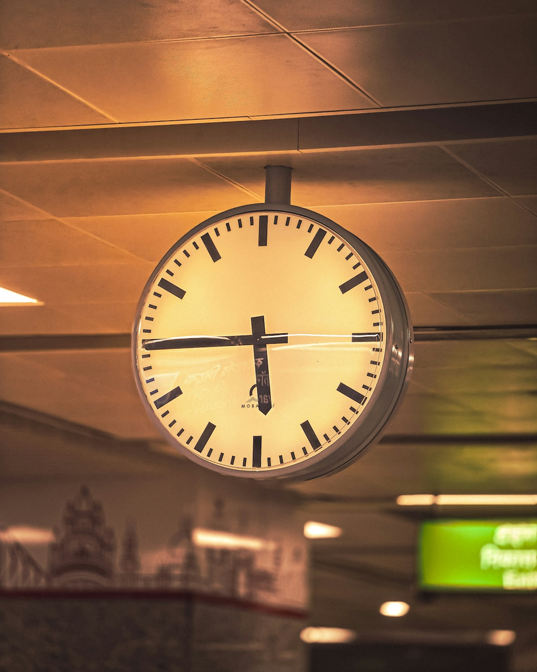 A clock hanging from the ceiling of a building