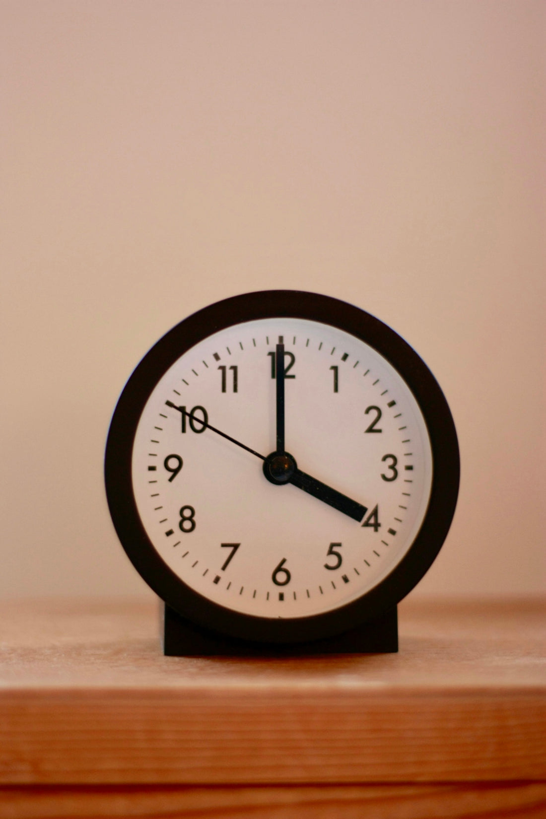 A black and white clock sitting on top of a wooden table