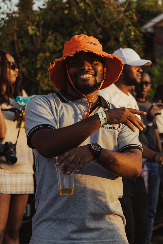 Man in orange hat holding drink, smiling at camera